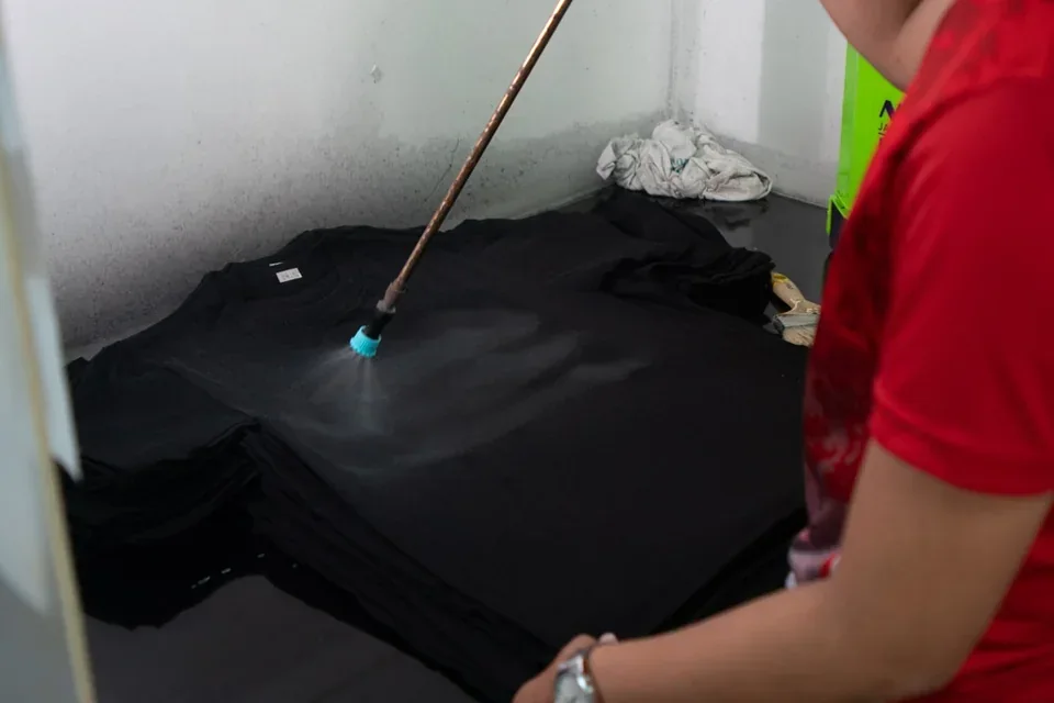 ทีมงานพ่น Pretreatment บนเสื้อสีดำสำหรับงาน DTG